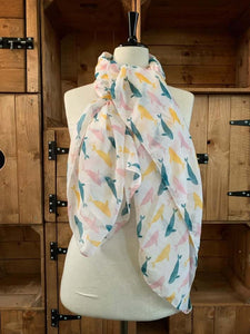Image of the story extract scarf 'Extract from tales with whales' with a printed repeating pattern of yellow, teal and pale pink whales on a white background. Scarf displayed tied around a mannequin.