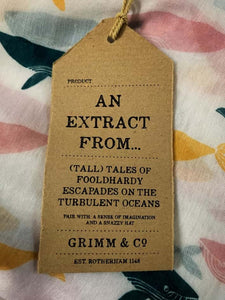 Image of the story extract scarf 'Extract from tales with whales' with a printed repeating pattern of yellow, teal and pale pink whales on a white background. Kraft paper labels is shown with description 'An extract from (tall) tales of foolhardy escapades on the turbulent oceans'. 