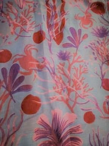 Image of the story extract scarf 'Extract from a tale under the sea' with a printed pattern of rockpool plants and creatures such as seaweed and crabs in purples and pinks. Image shows detail of full print pattern.