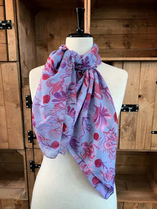 Image of the story extract scarf 'Extract from a tale under the sea' with a printed pattern of rockpool plants and creatures such as seaweed and crabs in purples and pinks. Scarf displayed tied around a mannequin.