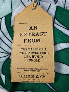 Image of the story extract scarf 'Extract from a tale in the jungle (green leaves)' with a printed pattern of large tropical stems with white tropical and leafy flowers with leaves on a bright green background. Kraft paper label is shown with description 'An extract from the tales of wild adventure in a humid jungle'.