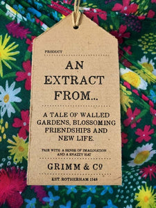 Image of the story extract scarf 'Extract from a tale of gardens' with a printed pattern of stylized daisies, forget-me-nots, dandelions and tiny pink flowers on a grass-green background. Kraft paper label is shown with description of 'an extract from a tale of walled gardens, blossoming friendships and new life'.