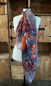 Image of the story extract scarf 'Extract from a tale of windswept abbeys' with an abstract printed pattern of of red, orange white, steel blue and navy blue splatters on a background of light grey. Scarf displayed tied around a mannequin.