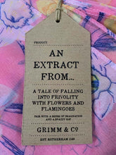 Load image into Gallery viewer, Image of the story extract scarf &#39;Extract from a tale in a land of wonder&#39; with a printed pattern of yellow, pale pink and white daffodils with purple stems and leaves on a baby pink background. Kraft paper label is shown with description &#39;An extract from a tale of falling into frivolity with flowers and flamingos&#39;.