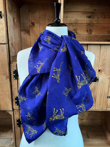 Image of the story extract scarf 'Extract from a tale in the jungle (tiger)' with a printed pattern of yellow tigers with dark blue stripes set on a background of royal blue. Scarf displayed tied around a mannequin.