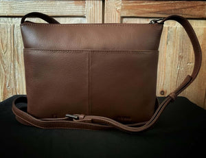 Image shows a brown Yoshi leather cross-body bag from the back view, showing a back slip pocket and the extendable strap. Design is plan brown leather on the back view.