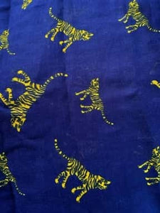 Image of the story extract scarf 'Extract from a tale in the jungle (tiger)' with a printed pattern of yellow tigers with dark blue stripes set on a background of royal blue. Image shows detail of full printed pattern.