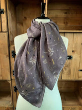 Load image into Gallery viewer, Image of the story extract scarf &#39;Extract from a tale of heroes&#39; with a printed pattern of zodiac constellations such as pegasus and little bear among shooting stars and distant planets in white and yellow on a background of lilac-grey. Scarf displayed tied around a mannequin.