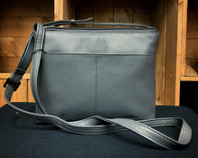 Load image into Gallery viewer, Image shows the back view of the Yoshi leather cross body bag in a dark grey. The bag design is of books by the Bronte sisters which appear on the front. Bag has a back slip pocket.