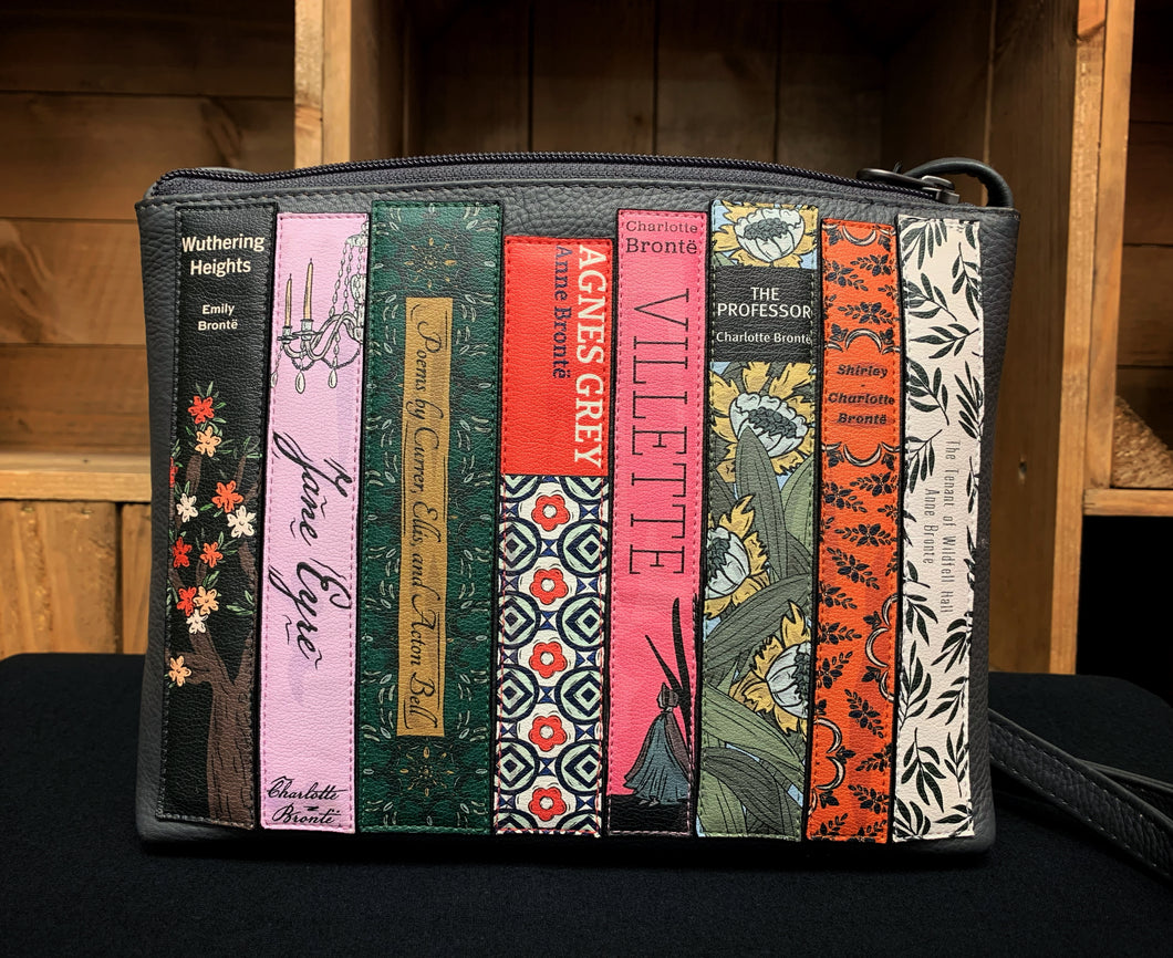 Image shows the Yoshi collection leather cross body bag featuring applique books by the Bronte sisters. Titles on the book spines include Villette, Jane Eyre and Wuthering Heights. 