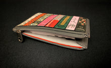 Load image into Gallery viewer, Image shows the Yoshi leather Coin Keeper purse  featuring the book titles of the Bronte Sisters appliqued across the front. Purse is dark grey leather with a white cotton lining printed with YOSHI in grey text. Purse shown with zipper open. 
