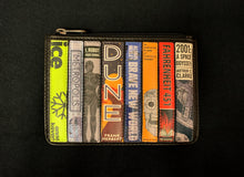 Load image into Gallery viewer, Image shows the Yoshi leather coin keeper featuring appliqued leather book spines in various colours and designs of Sci-Fi novels. Titles include Dune, I, Robot and Fahrenheit 451. Purse is black leather with a zipper across the top. 