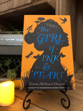 Load image into Gallery viewer, Image of the front cover of the paperback book The Girl of Ink and Stars, written by Kiran Millwood Hargrave. Displayed on a book stand with candles.