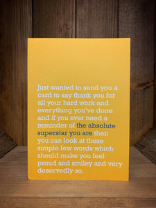 A yellow greetings card with white text saying 'Just wanted to send you a card to say thank you for all your hard work and everything you've done and if you ever need a reminder of the absolute superstar you are then you can look at these simple few words which should make you feel proud and smiley and very deservedly so.' The words 'the absolute superstar you are' are printed in dark blue.