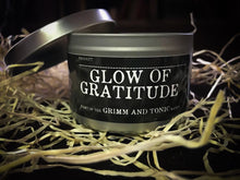 Load image into Gallery viewer, Image of Glow of Gratitude, a tinned candle with slip lid in the Grimm &amp; Tonic range. Tin is silver with a black label and white text