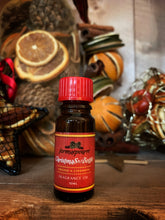 Load image into Gallery viewer, Image of the Christmas in a Bottle scented oil against a backdrop of pot pourri in the Scents of the Season range. Bottle is brown glass with a red top and label.