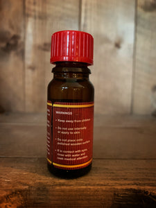 Image of the Christmas in a Bottle scented oil. Bottle is brown glass with a red top and label. Image shows the warning label - keep away from children, do not use internally or apply to skin, do not place onto polished wooden surface, if in contact with eyes, rinse with water and seek medical attention.