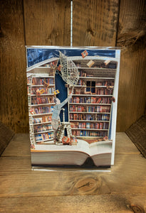 Image showing an A5 laser cut greetings card with a blue background (inside the card) and a cut out scene popping up from an open book showing bookshelves stacked with books and some of them are flying away. A man stands on a ladder with a net trying to catch them all for his collection. 