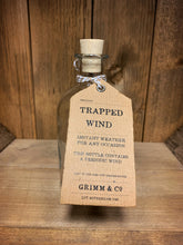 Load image into Gallery viewer, Image of the Trapped Wind bottle from the Airs and Graces range: An empty glass potion bottle with cork. The bottle has a kraft tag around  the neck, reading: Trapped Wind. Instant weather for any occasion. This bottle contains a periodic wind. 