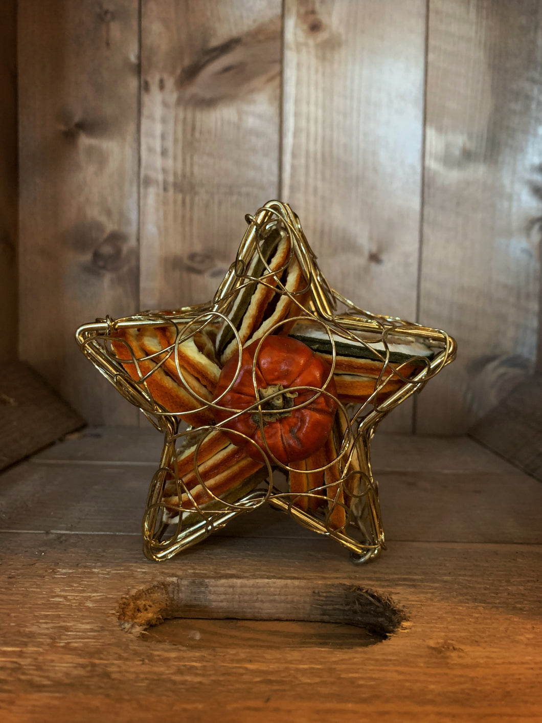 Image of Scent of the Season Star Centrepiece, a gold wire box in the shape of a star filled with pot pourri including dried orange and green orange slices and a dried mini pumpkin
