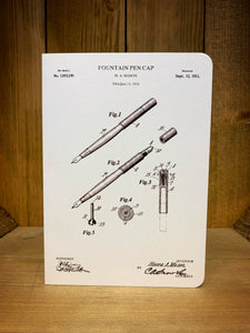 Image of a black and white greetings card printed on pearlescent card with a sketched design of a fountain pen patent with 3 Fig images detailing parts of the pen and the patent date of 12 September 1911 on the top right corner.