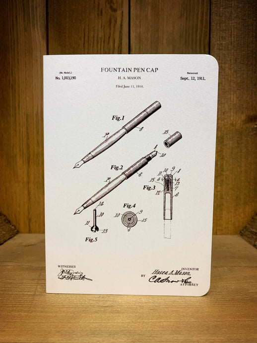 Image of a black and white greetings card printed on pearlescent card with a sketched design of a fountain pen patent with 3 Fig images detailing parts of the pen and the patent date of 12 September 1911 on the top right corner.