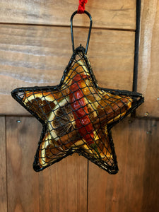 Image of the Scent of the Season Tree Decoration shaped as a star. Decoration is a black wire shaped hanging box with hanging loop and ribbon. Box is filled with pot pourri including dried orange and green orange slices, a dried red chilli and cinnamon stick