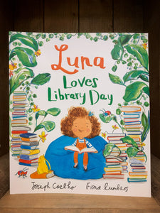 Image showing the front cover of Luna Loves Library Day with a bright illustration of Luna sat on a beanbag surrounded by books and jungle foliage.