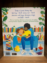 Load image into Gallery viewer, Image showing the back cover of Luna Loves Library Day with an illustration of Luna and her dad sat in a blue hair in the library with piles and shelves of books as they read together.