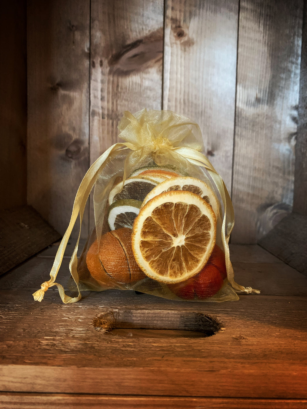 Image of the small gold organza fabric bag of pot pourri including cinnamon sticks, dried whole oranges, dried orange and green orange slices and a dried mini pumpkin