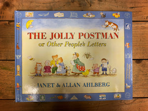 Image of the front cover of hardback book The Jolly Postman or Other People's Letters with an illustration showing many well-known fairy tale characters reading letters on a pale yellow background surrounded by a blue border.