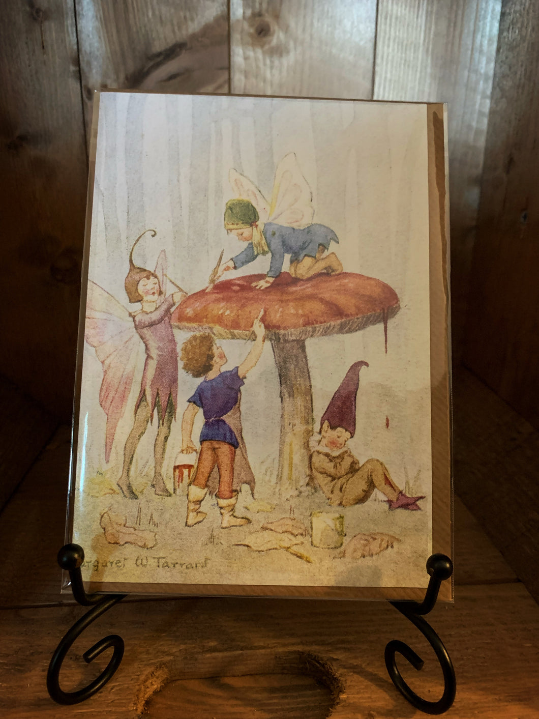 Image of greetings card Fairy Land with Toadstool, a full-colour watercolour style illustration of four fairies painting a toadstool in a woodland scene