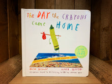 Load image into Gallery viewer, Image shows the front cover of the board book The Day The Crayons Came Home with Pea Green crayon standing on a postcard with a knapsack over their shoulder. 