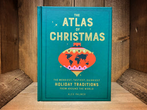 Image showing the front cover of the hardback book The Atlas of Christmas with a dark green background and golden text featuring graphic illustration of a tree bauble with a map of the world inside.