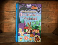 Load image into Gallery viewer, Image showing the book-shaped jigsaw library featuring Alice&#39;s Adventures in Wonderland. Cover showcases Alice, Mad Hatter and March Hare sat at the Unbirthday tea party with the Cheshire Cat sat above.