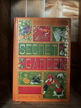 Load image into Gallery viewer, Image showing The Secret Garden MinaLima edition book with an orange clothbound cover printed with gold, red and olive green and showcasing mini illustrations from the tale, such as the robin, a key, a fox, some squirrels and Mary, Dickson and Colin with a picnic in the garden.