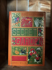 Image showing The Secret Garden MinaLima edition book with an orange clothbound cover printed with gold, red and olive green and showcasing mini illustrations from the tale, such as the robin, a key, a fox, some squirrels and Mary, Dickson and Colin with a picnic in the garden.