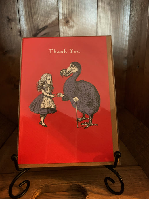 Image of the greetings card Alice Dodo Thank You with a red background and a black and white illustration of Alice and the Dodo with elements coloured blue and the words Thank You across the top.