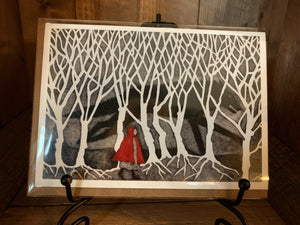 Image shows the greetings card Into the Dark Woods showing a scene from Red Riding Hood with the wolf hiding in the shadows of the trees.