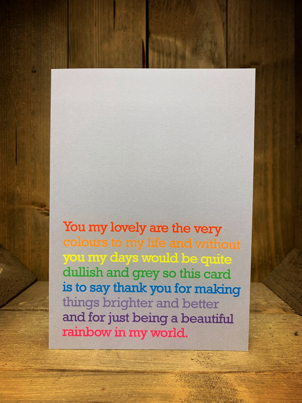 Image of the light grey coloured greetings card with a rainbow typed message on the front reading,' You my lovely are the very colours to my life and without you my days would be quite dullish and grey so this card is to say thank you for making things brighter and better and for just being a wonderful rainbow in my world.' The text per line varies from red, orange, yellow, green, blue, lavender, purple and pink with the inside left blank.