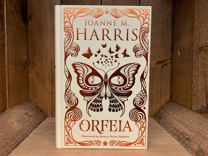 Image shows the front cover of the book Orfeia. The book is bound in cream coloured cloth, with the title, and flowing patterns and butterfly  illustrations embossed in bronze.