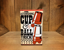 Load image into Gallery viewer, Image shows the front of the box for the Cup &amp; Ball Trick. It has an illustration showing the parts of the trick included.