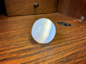 Image shows a close up view of  the sphere shaped Blue Moon Crystal (selenite crystal).