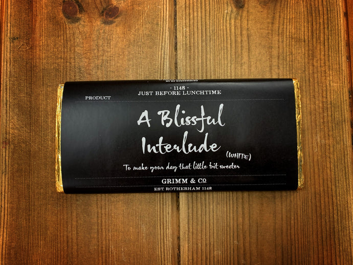 Image shows the white Chocolate A Blissful Interlude bar with black label, white text and gold foil.